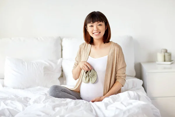 Mulher grávida feliz com botas na cama em casa — Fotografia de Stock