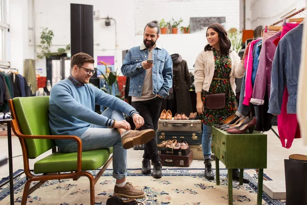 Amigos escolhendo roupas na loja de roupas vintage — Fotografia de Stock