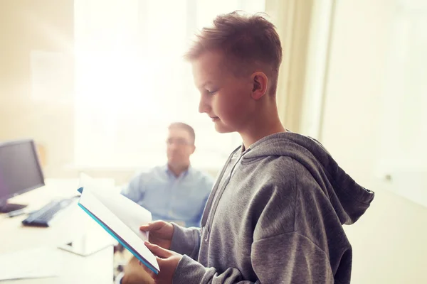 Aluno menino com caderno e professor na escola — Fotografia de Stock