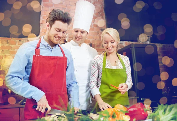 Gelukkige paar en mannelijke chef kok koken in de keuken — Stockfoto