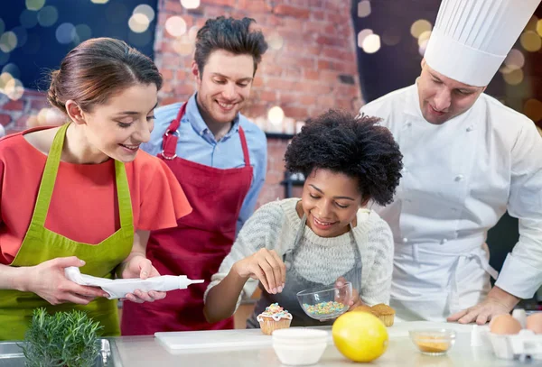 Amigos felizes e cozinheiro chef assar na cozinha — Fotografia de Stock