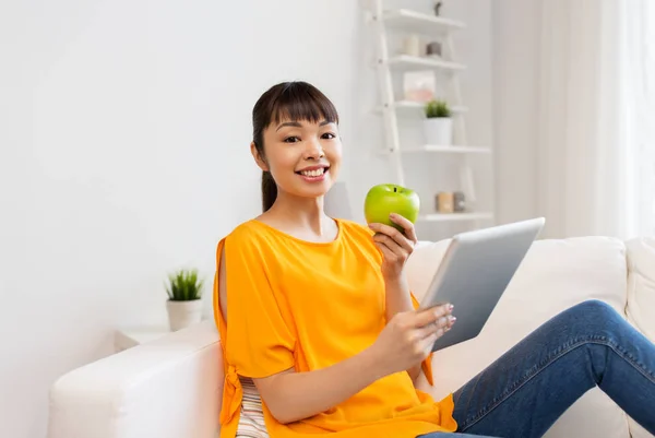 Happy asian woman with tablet pc and apple at home — Stock Photo, Image