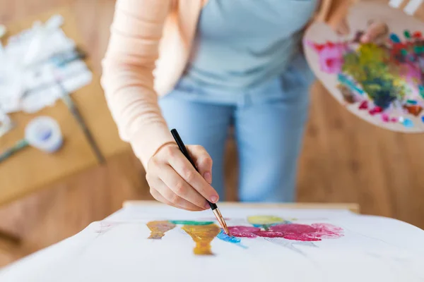 Künstler mit Palette und Pinselmalerei im Atelier — Stockfoto