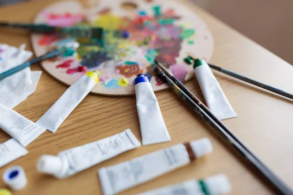 Palette, brushes and paint tubes on table — Stock Photo, Image