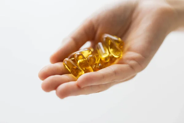 Hand holding cod liver oil capsules — Stock Photo, Image