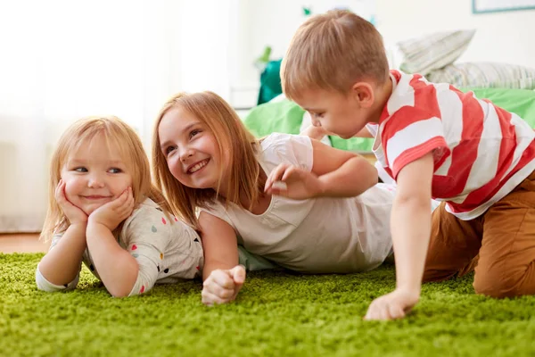 Niños pequeños y felices tumbados en el suelo o la alfombra —  Fotos de Stock
