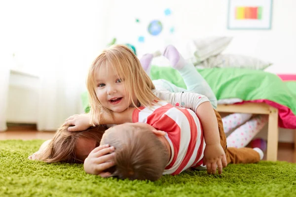 Niños pequeños y felices tumbados en el suelo o la alfombra — Foto de Stock