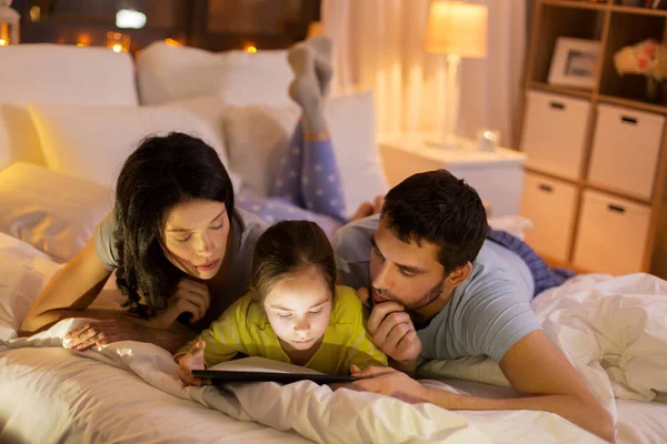 Familia con tableta pc en la cama por la noche en casa —  Fotos de Stock