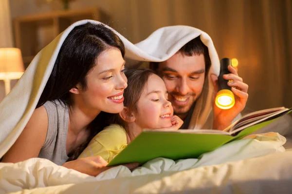 Gelukkige familie leesboek in bed bij nacht thuis — Stockfoto