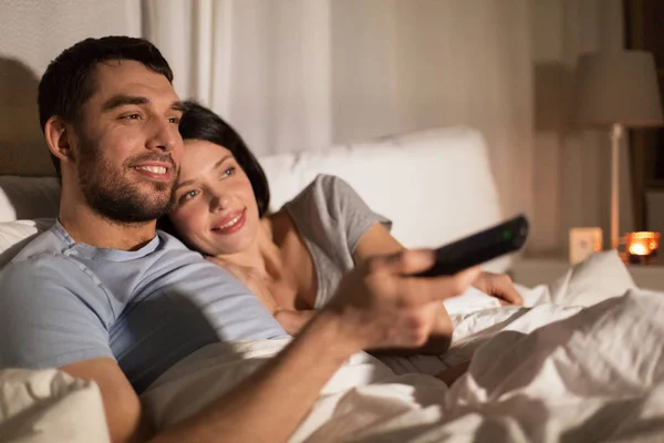 Šťastný pár sledování televize v posteli v noci doma — Stock fotografie
