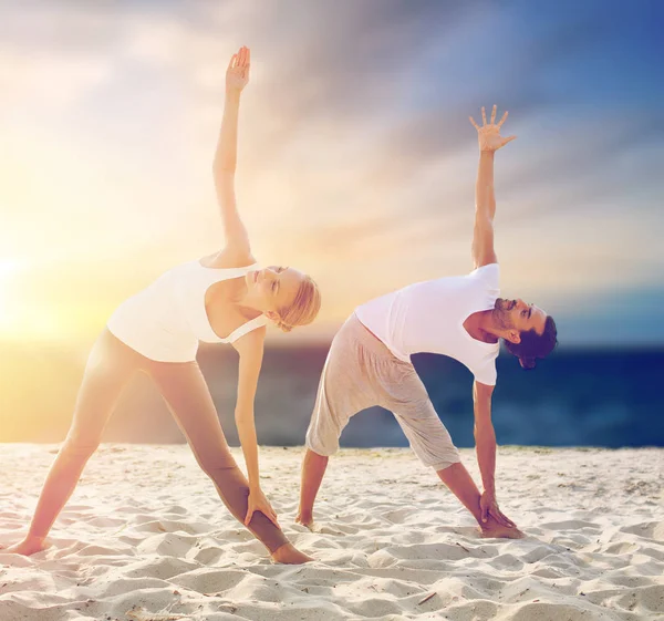 Çift sahilde yoga egzersizleri yapma — Stok fotoğraf