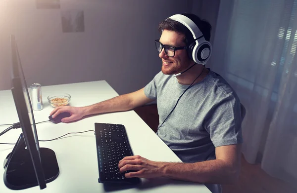 Мужчина в гарнитуре играет дома в компьютерную видеоигру Лицензионные Стоковые Изображения