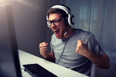 man in headset playing computer video game at home clipart