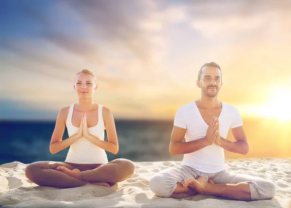 Paar maken van yoga en mediteren op strand — Stockfoto
