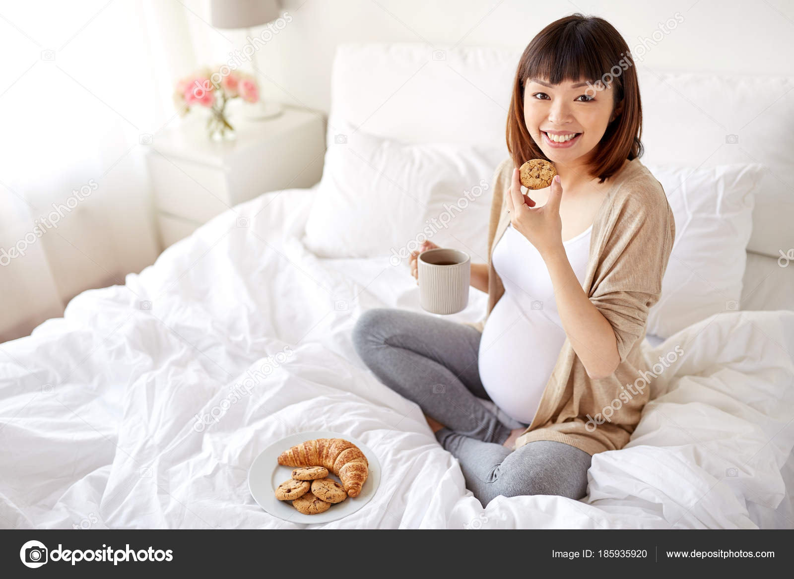 Happy pregnant woman eating cookie in bed at home — Stock Photo © Syda