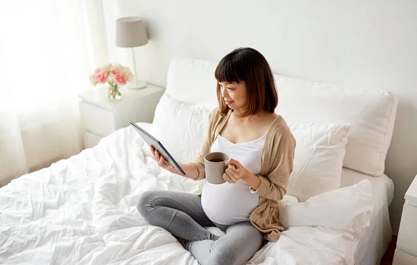 Gelukkig zwanger aziatische vrouw met tablet pc thuis — Stockfoto