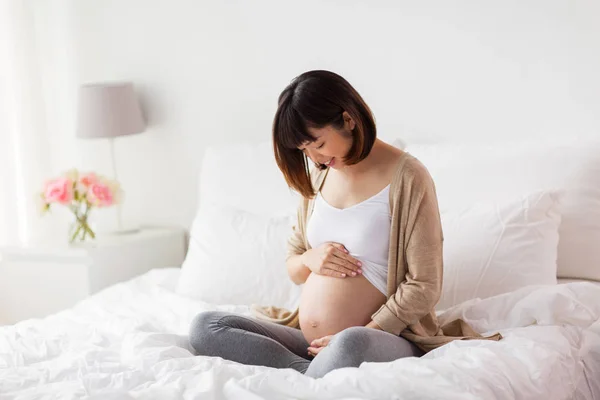 Heureux enceinte asiatique femme assis dans lit à la maison — Photo