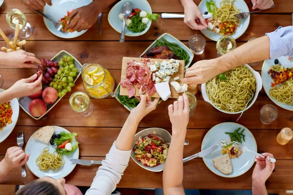 Grupo de personas que comen en la mesa con alimentos — Foto de Stock