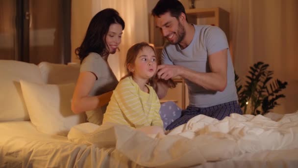 Otec, pletení vlasy dceru v posteli v noci — Stock video