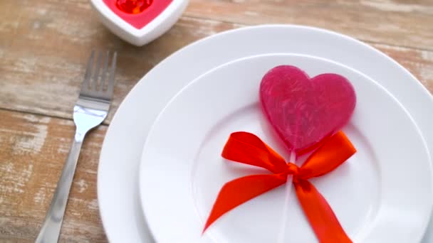 Κοντινό πλάνο του κόκκινη καρδιά σχήμα γλειφιτζούρι στο πιάτο — Αρχείο Βίντεο