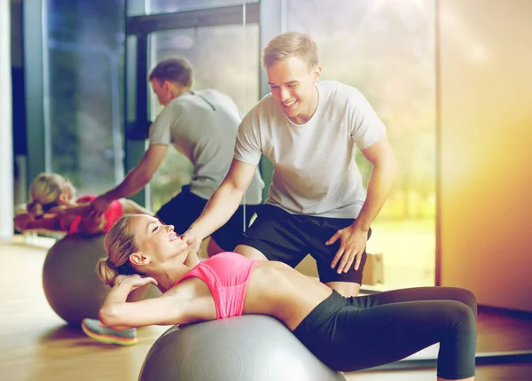 Sorrindo jovem mulher com personal trainer no ginásio — Fotografia de Stock