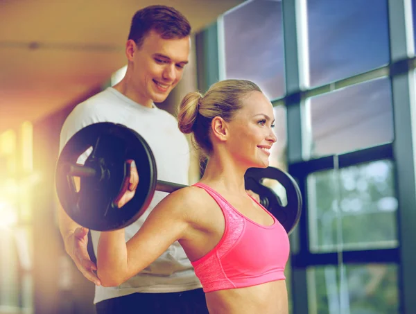 Smiling man and woman with barbell in gym — Stock Photo, Image