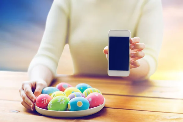 Perto de mãos com ovos de Páscoa e smartphone — Fotografia de Stock