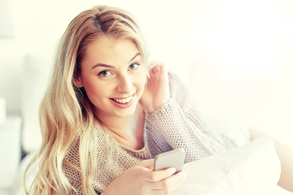Ευτυχισμένος νεαρή γυναίκα με το smartphone στο κρεβάτι στο σπίτι — Φωτογραφία Αρχείου