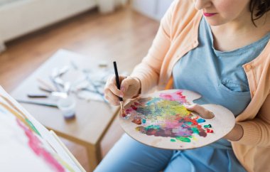 artist with palette and brush painting at studio clipart