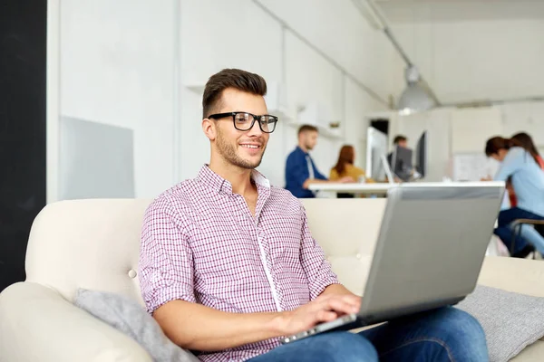 Uomo sorridente con computer portatile che lavora in ufficio — Foto Stock