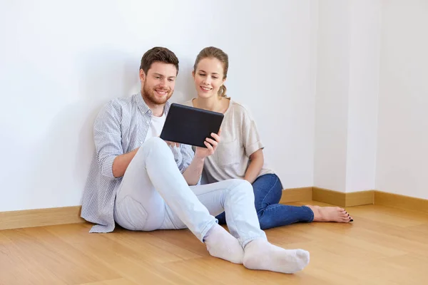 Casal feliz com computador tablet pc em nova casa — Fotografia de Stock