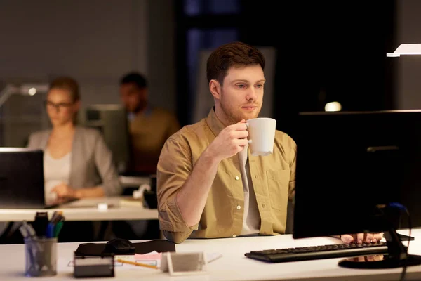 Homem com laptop e café trabalhando no escritório da noite — Fotografia de Stock