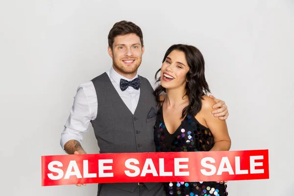 Счастливая пара с красным знаком продажи — стоковое фото
