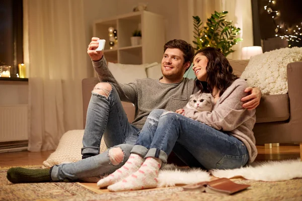 Feliz pareja tomando selfie por teléfono inteligente en casa —  Fotos de Stock