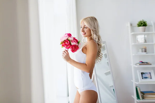 Frau in Unterwäsche mit Blumenstrauß am Fenster — Stockfoto