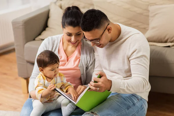 Lycklig familj med baby läsebok hemma — Stockfoto