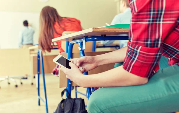 Estudiante chico con teléfono inteligente mensajes de texto en la escuela — Foto de Stock