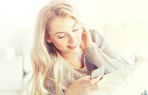 Glad ung kvinna med smartphone i sängen hemma — Stockfoto