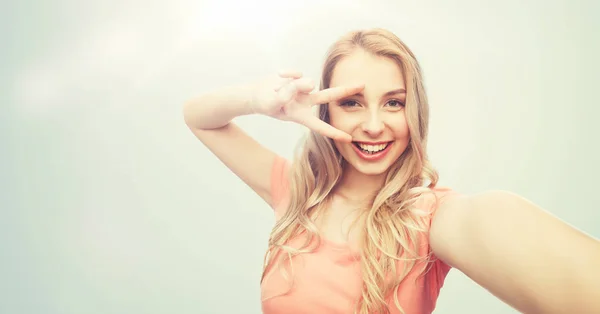 Sorrindo mulher tomando selfie e mostrando sinal de paz — Fotografia de Stock