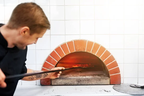 피자 집에서 오븐에 피자를 배치 하는 껍질을 가진 남자 — 스톡 사진