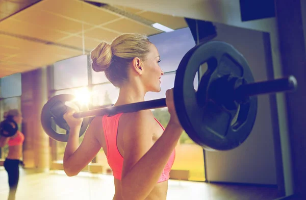 Mujer deportiva haciendo ejercicio con barra de pesas en el gimnasio —  Fotos de Stock