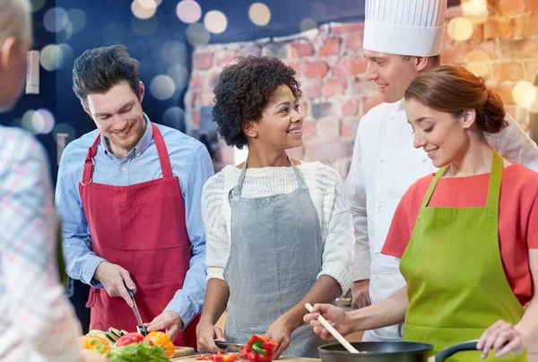 Happy friends and chef cook cooking in kitchen — Stock Photo, Image