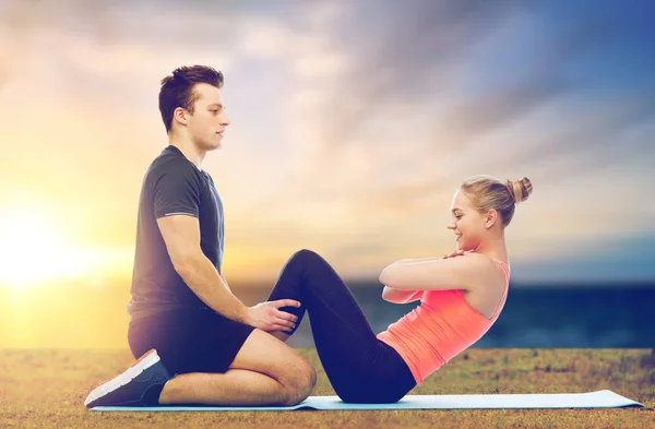 Feliz casal esportivo fazendo sit-ups ao ar livre — Fotografia de Stock