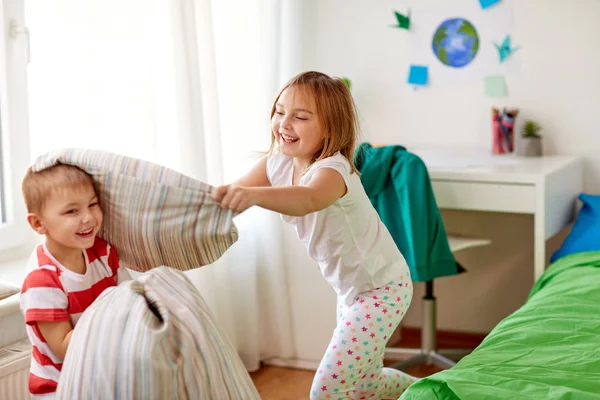 Kids playing and fighting by pillows at home — Stock Photo, Image