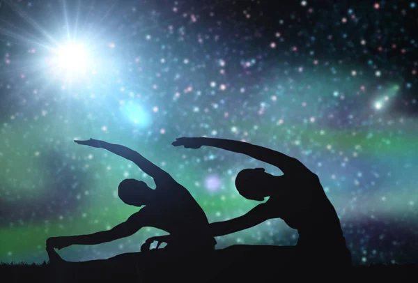 Пара делает упражнения йоги на космическом фоне — стоковое фото