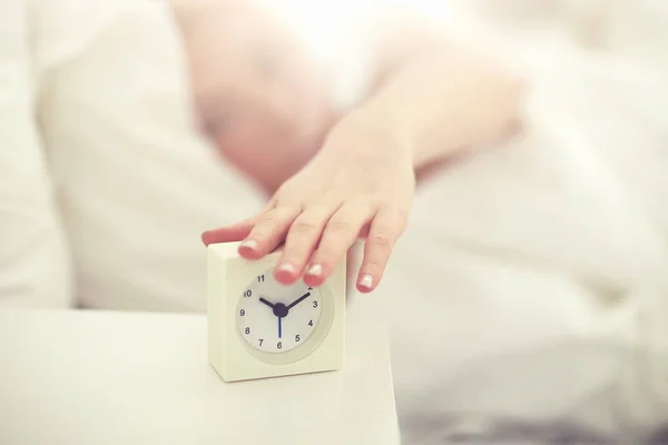 Primer plano de la mujer con despertador en la cama en casa —  Fotos de Stock