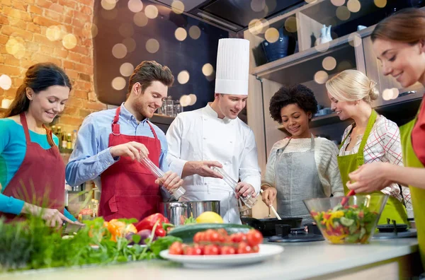 Happy friends and chef cook cooking in kitchen — Stock Photo, Image