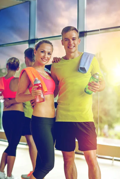 Pareja sonriente con botellas de agua en el gimnasio —  Fotos de Stock