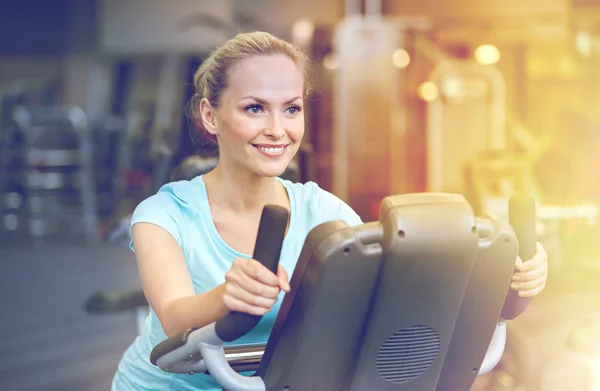 Leende kvinna utövar på motionscykel i gym — Stockfoto