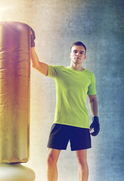 Hombre con guantes de boxeo y saco de boxeo en el gimnasio —  Fotos de Stock